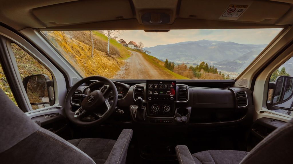 Blick aus dem Fahrerhaus über die Drehsitze auf eine Bergstraße